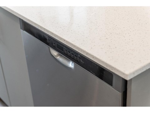 A dishwasher with a silver handle and a white countertop.