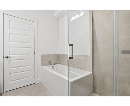 A white door is open to a bathroom with a glass shower door.