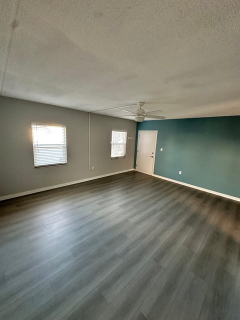 A room with a ceiling fan and two windows.