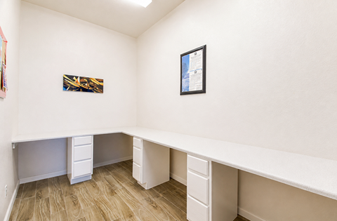 A white desk with drawers is in a room with wood flooring.