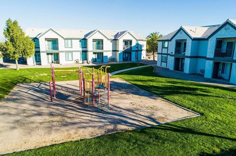 A playground with a swing set is in front of a row of houses.