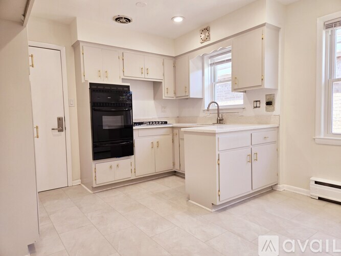 A kitchen with white cabinets and a black oven.