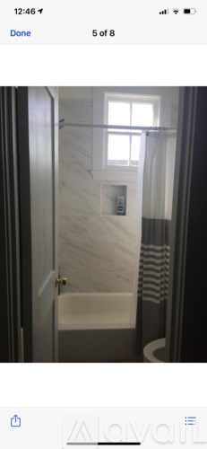 A bathroom with a white bathtub and a window above it.