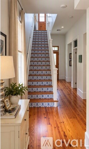 A staircase with a blue and white patterned runner leads up to a bright room.