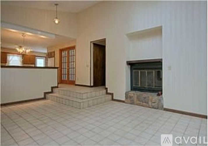 A large open room with a fireplace and a staircase leading to a landing.