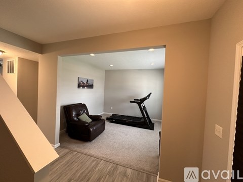 A living room with a brown leather chair and a black treadmill.