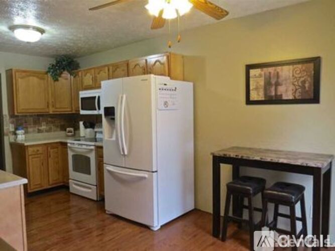 A white refrigerator is in the middle of a kitchen with wooden cabinets.