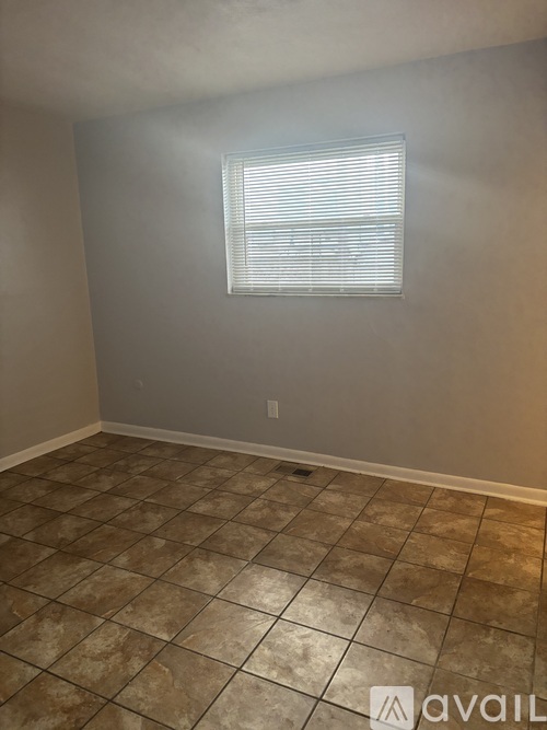 A room with a tiled floor and a window with blinds.
