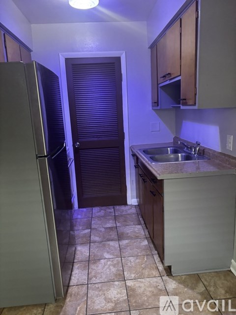 A kitchen with a refrigerator, sink and cabinets.