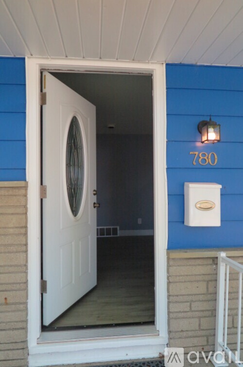 A white door with a round window is open to a hallway.
