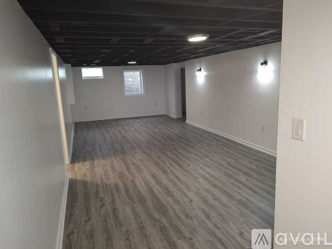 A spacious room with wooden flooring and white walls.