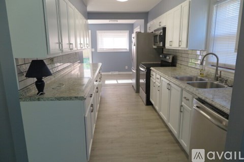 A kitchen with white cabinets and a marble countertop.