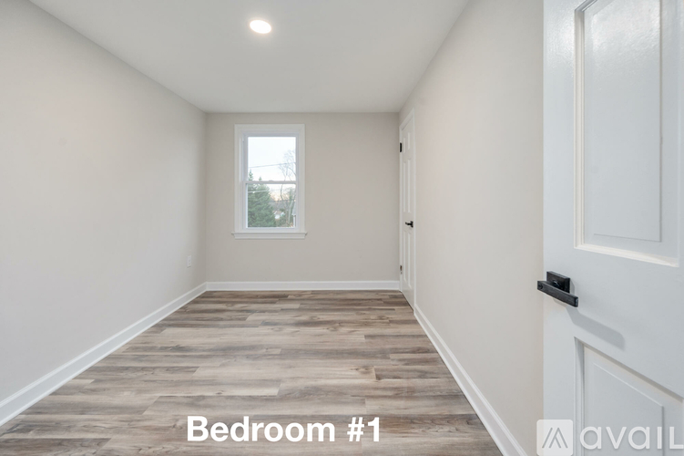 A spacious bedroom with wooden flooring and a window.