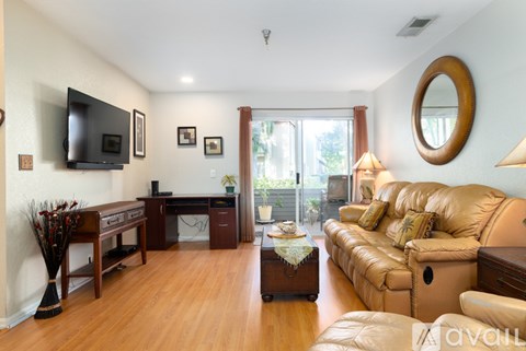 A living room with a tan couch and a wooden floor.