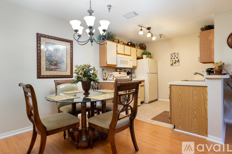 A kitchen with a table and chairs in the foreground and a framed picture on the wall.