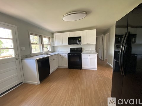 A kitchen with white cabinets and black appliances.