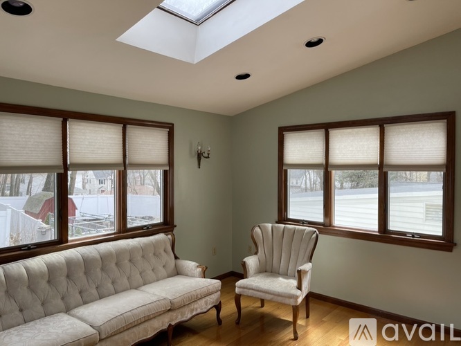 A living room with a white couch, a chair, and a skylight.