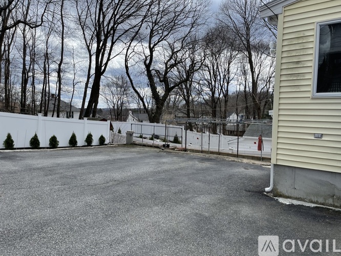 A parking lot with a fence and trees in the background.