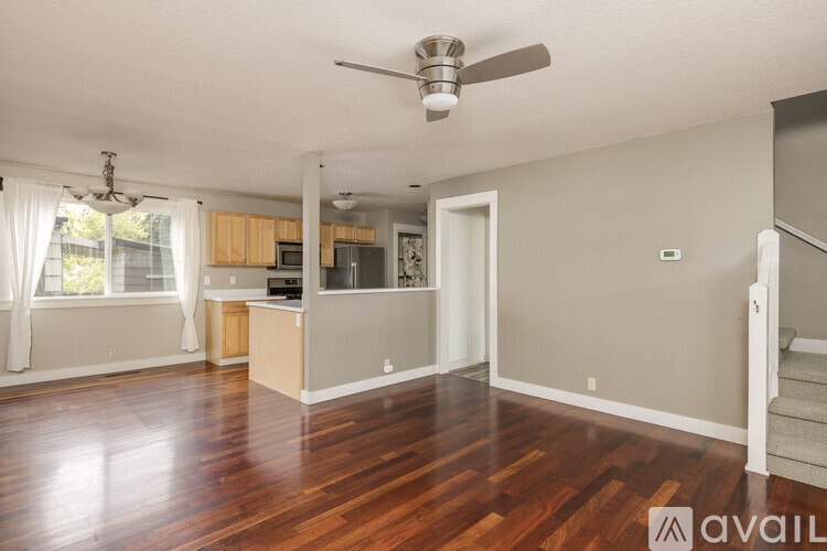 A spacious living room with hardwood floors and a ceiling fan.