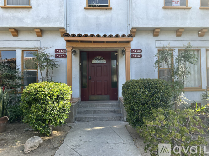 A white house with a red door and a brown roof.