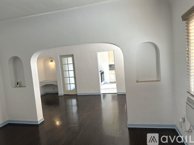 A spacious room with arched doorways and a wooden floor.