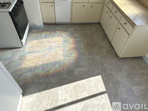 A kitchen with white cabinets and a tiled floor.