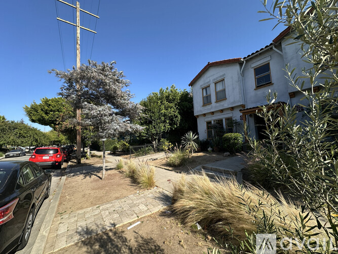 A residential area with a house, cars, and trees.