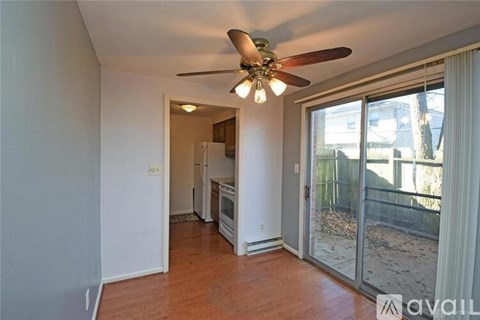 A room with a ceiling fan and sliding glass doors leading to a backyard.