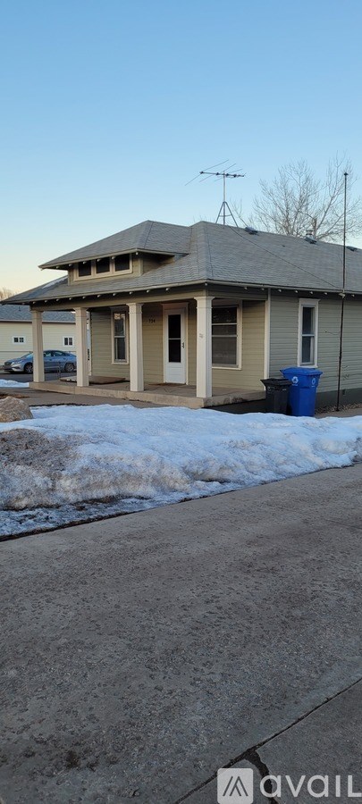 A house with a grey roof and a blue trash can in front.