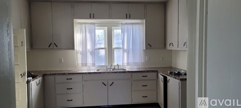 A kitchen with white cabinets and a window.