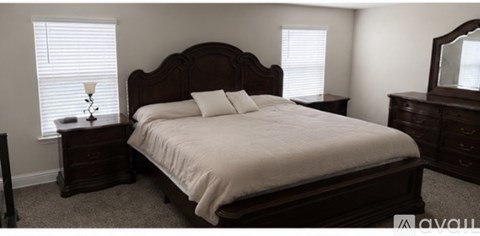 A bedroom with a large bed and a wooden headboard.