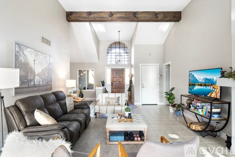 A living room with a black leather couch and a white furry chair.