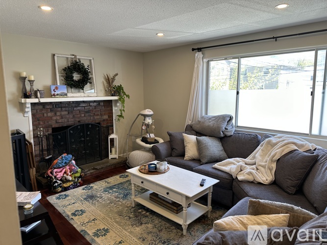 A living room with a grey couch, a white coffee table, and a fireplace with a wreath on top.