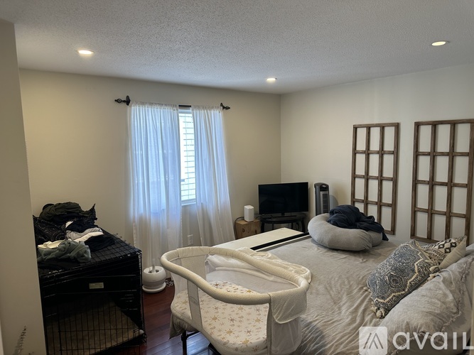 A bedroom with a white bed and a TV in the corner.