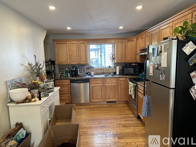 A kitchen with wooden cabinets and a black fridge.