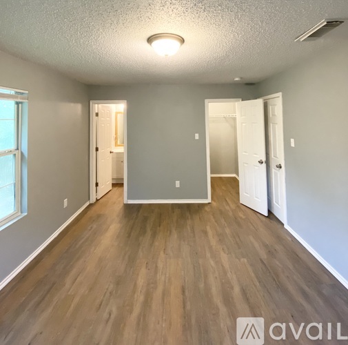 A spacious room with wooden flooring and white walls.