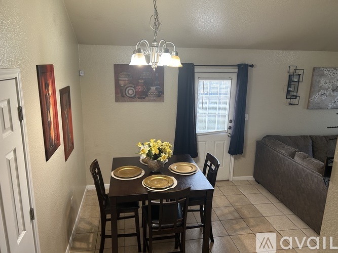 A dining room with a table set for two and a chandelier hanging from the ceiling.