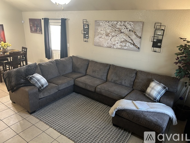 A grey sectional sofa with a pillow and a blanket on it.