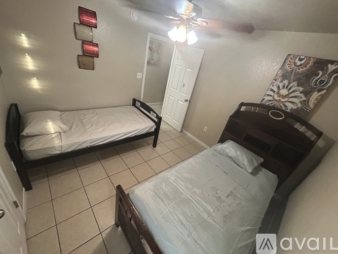 A bedroom with two beds and a ceiling fan.