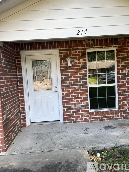 A white door with a glass window is on a brick house.