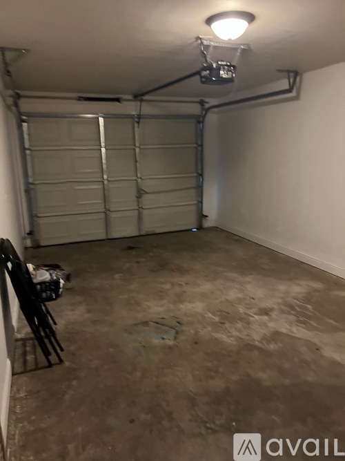 A garage with a closed shutter door and a chair.