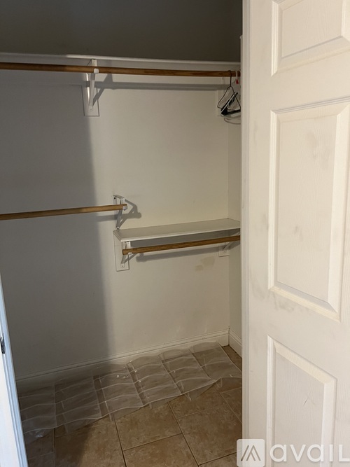 A white door is open to a room with a tiled floor and a shelf with hooks.