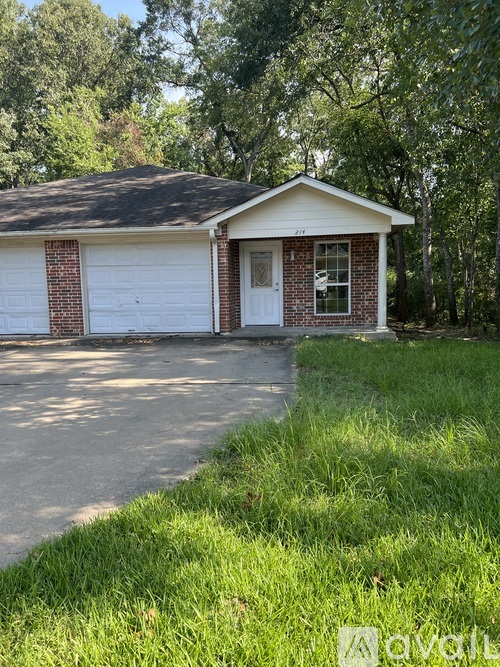 A two-car garage with a white door and windows is surrounded by green grass and trees.