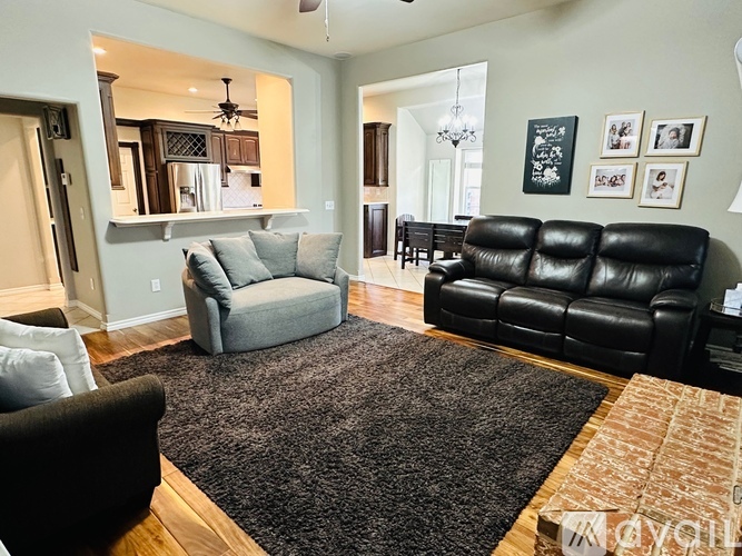 A living room with a black leather couch and a grey armchair.