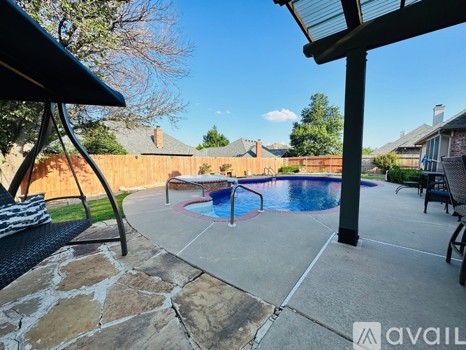 A backyard with a pool and patio furniture.