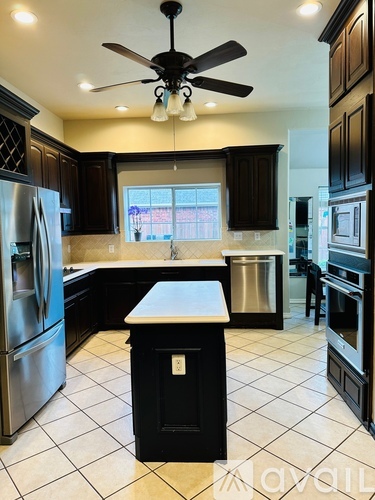 A kitchen with black cabinets and a white island.