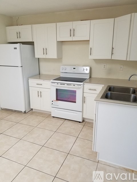 A kitchen with white appliances and cabinets.