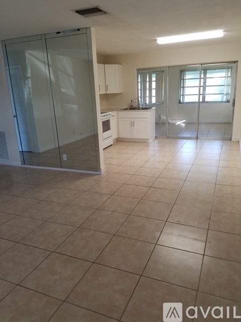 A tiled kitchen and living room with a glass door.