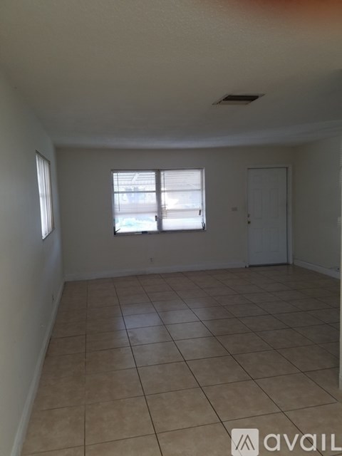 A room with tiled flooring and a window with blinds.