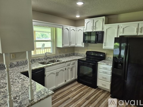 A kitchen with black appliances and white cabinets.
